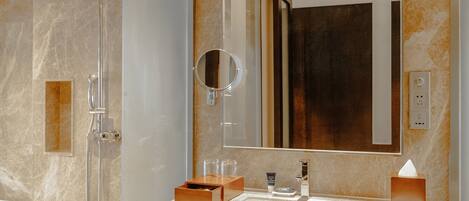 Un baño moderno con ducha de vidrio, lavamanos de mármol y un espejo grande.