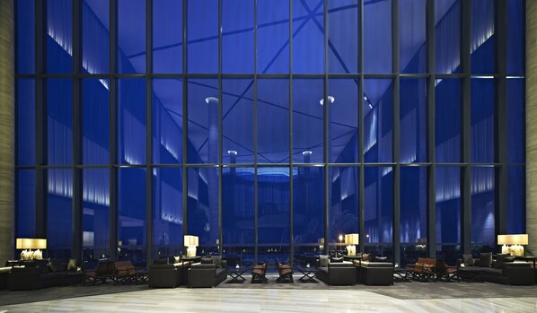 Un vestíbulo amplio con ventanas grandes, mobiliario moderno y un techo alto.