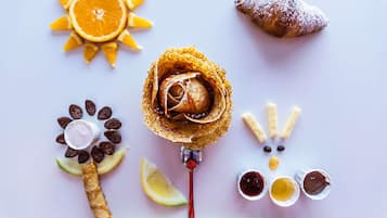 A dessert arrangement with a rose, orange slices, a croissant, chocolate pieces, and a sandwich.