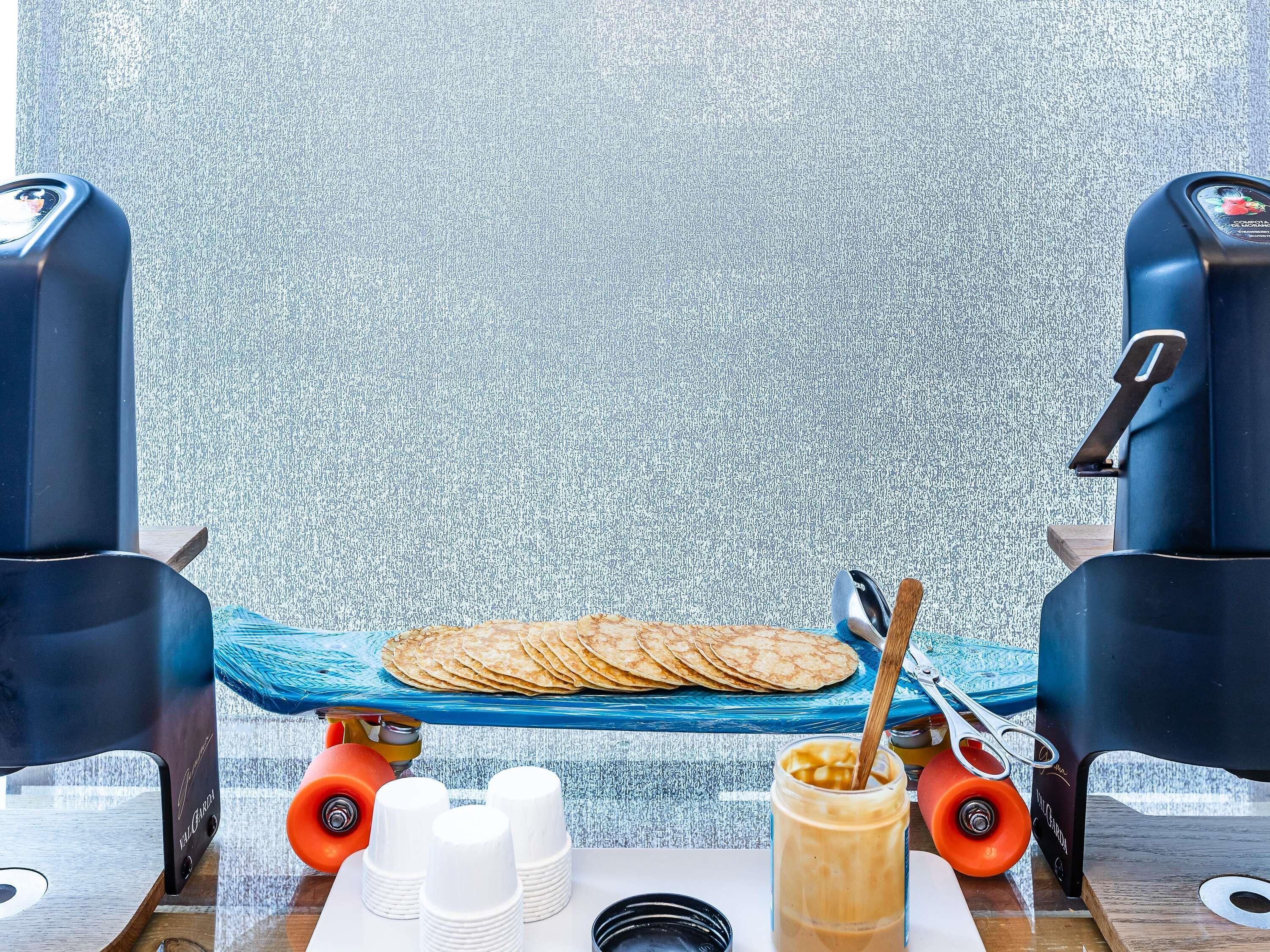 Una preparación para el desayuno con una bandeja azul, pan plano, un tarro de café y tazas de naranja.