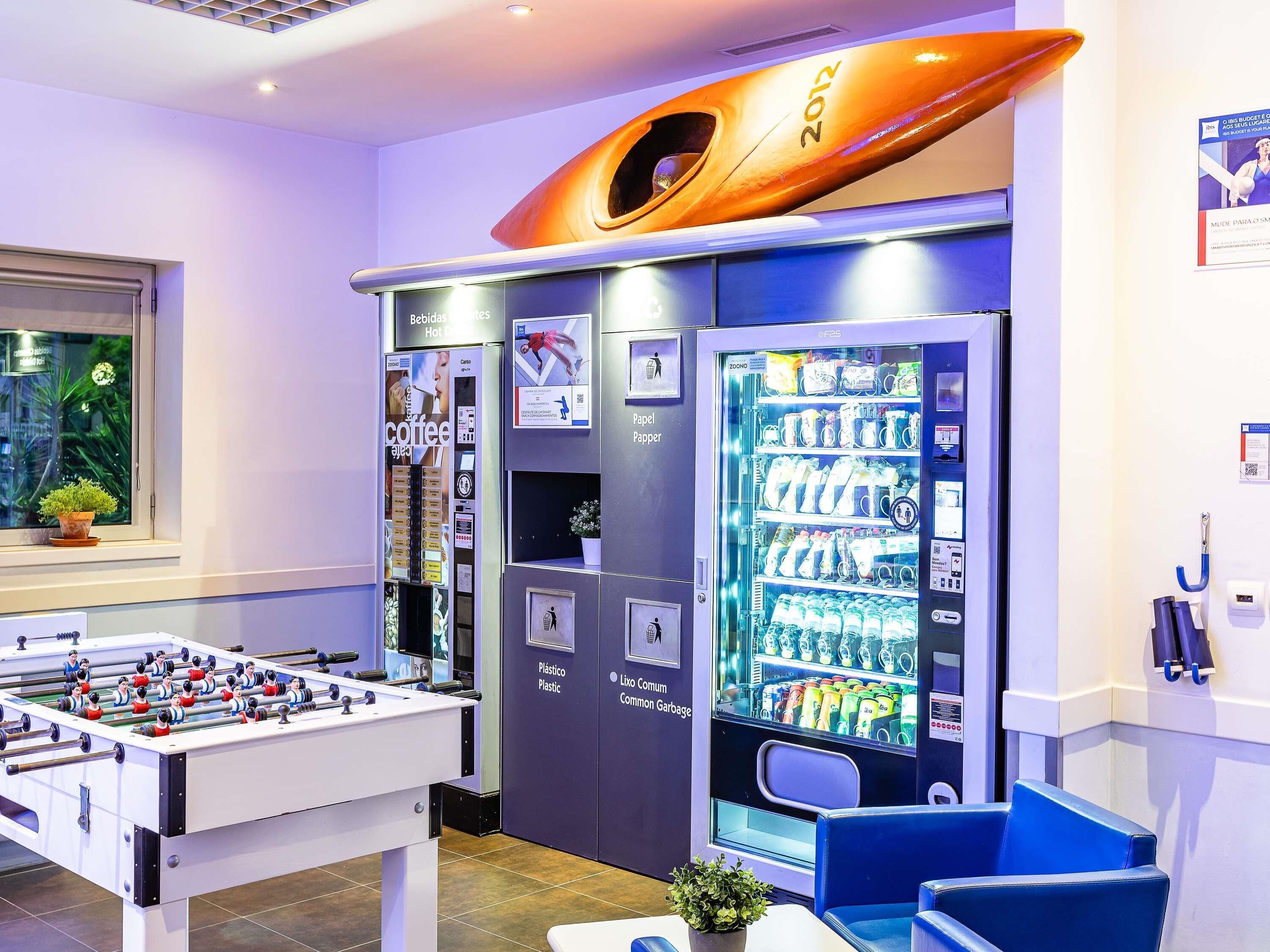 Een kamer met een tafelvoetbaltafel, automaten en een kajak.
