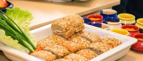 Un plato rectangular blanco con pan en rodajas cubierto de semillas, acompañado de una guarnición de lechuga y cebollas verdes.