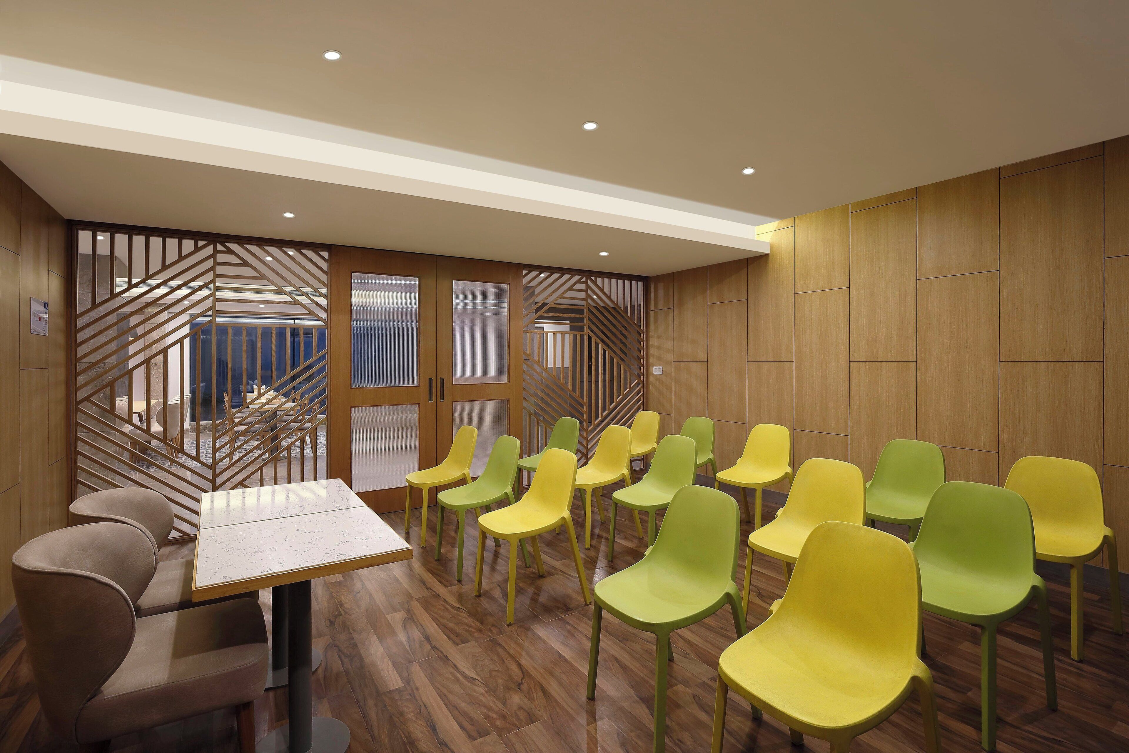 Sala de conferências com uma mesa comprida, várias cadeiras, painéis de madeira e vista através de um painel de vidro.