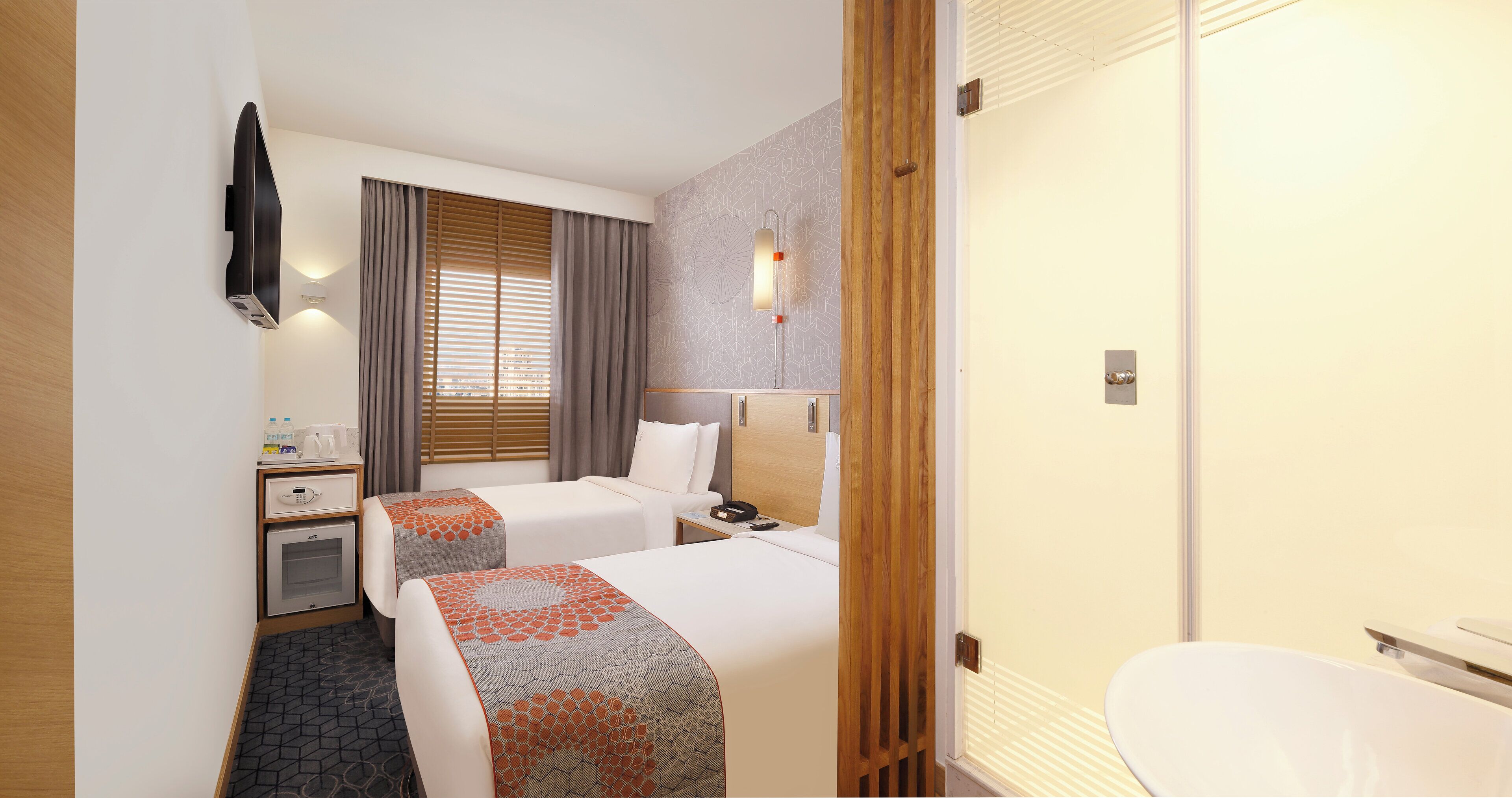 Une chambre d’hôtel avec deux lits, un bureau, un minibar, une télévision et une salle de bain.