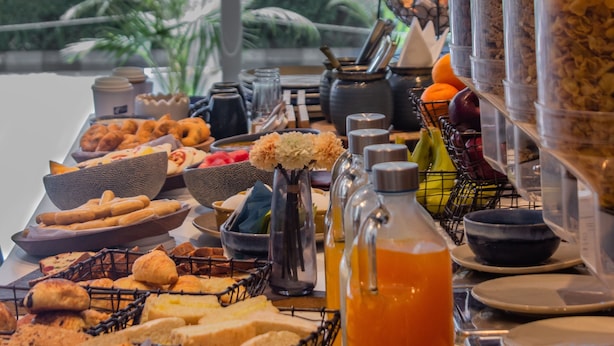 En buffet med forskellige spisemuligheder og drikkevarer, blandt andet brød, kager og en juiceautomat.