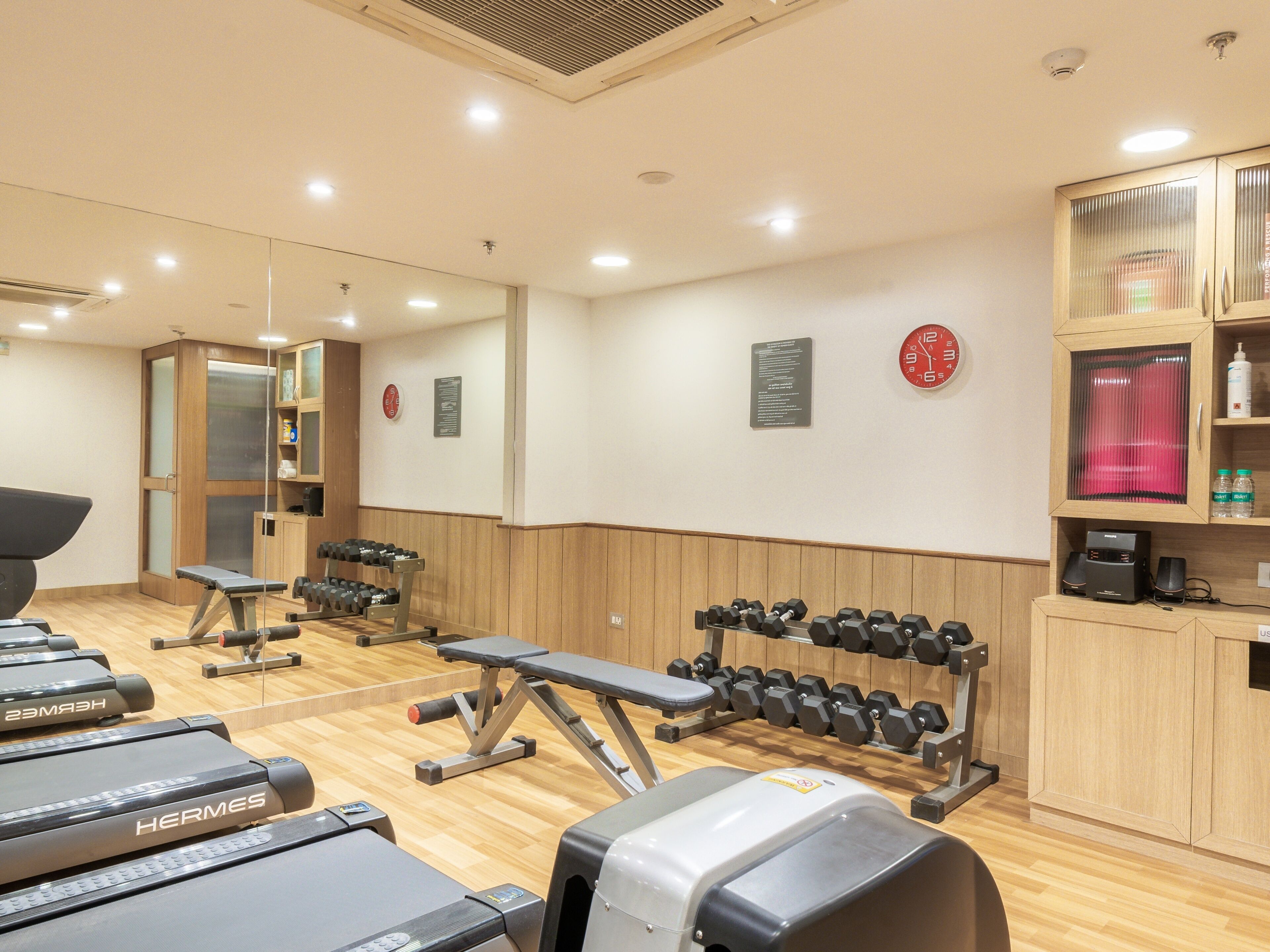 Et fitnesscenter med løbebånd, håndvægte og træningsudstyr.