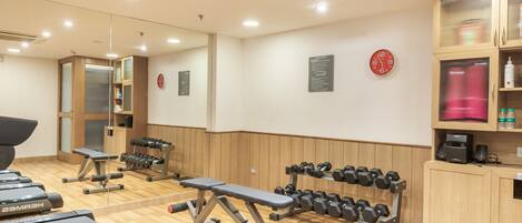 Et fitnesscenter med løbebånd, håndvægte og træningsudstyr.