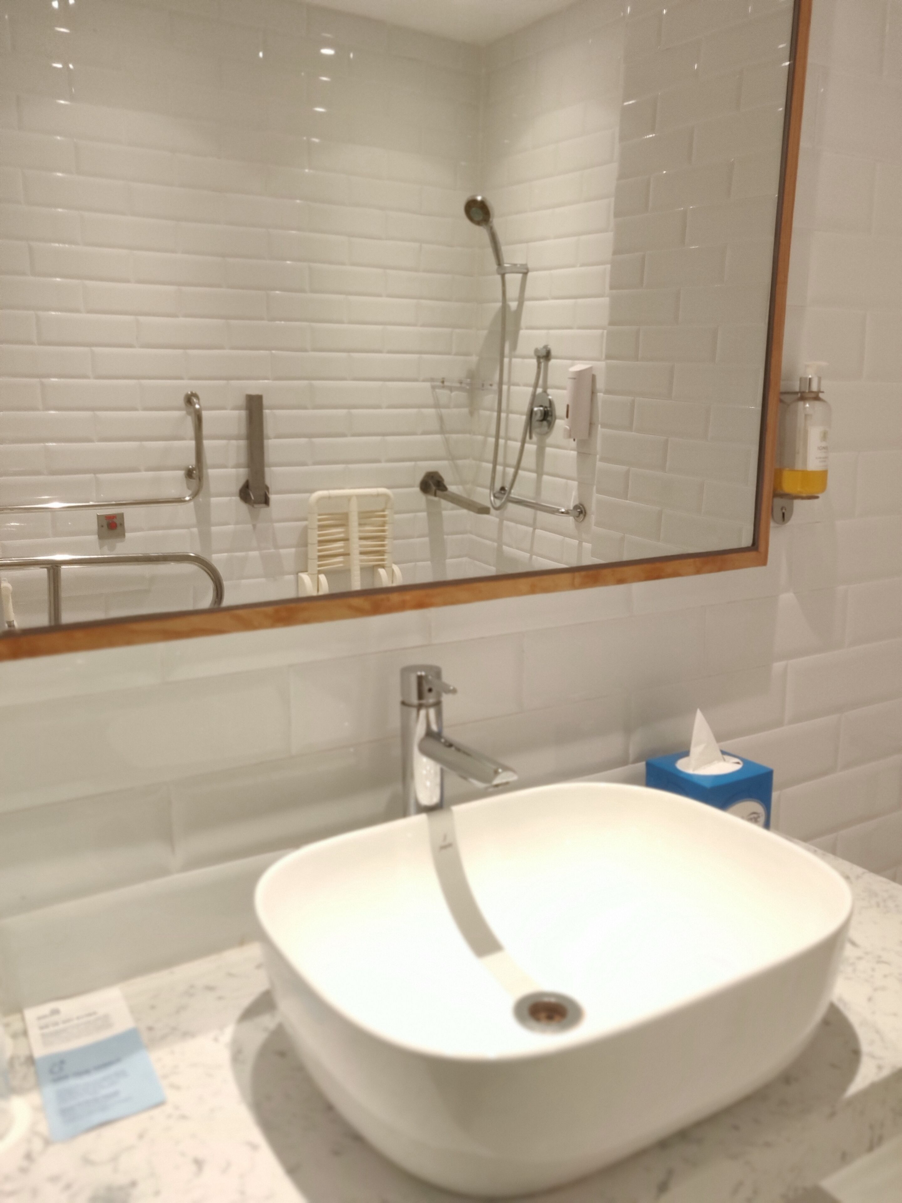 A bathroom with a white sink, a mirror, and a shower.