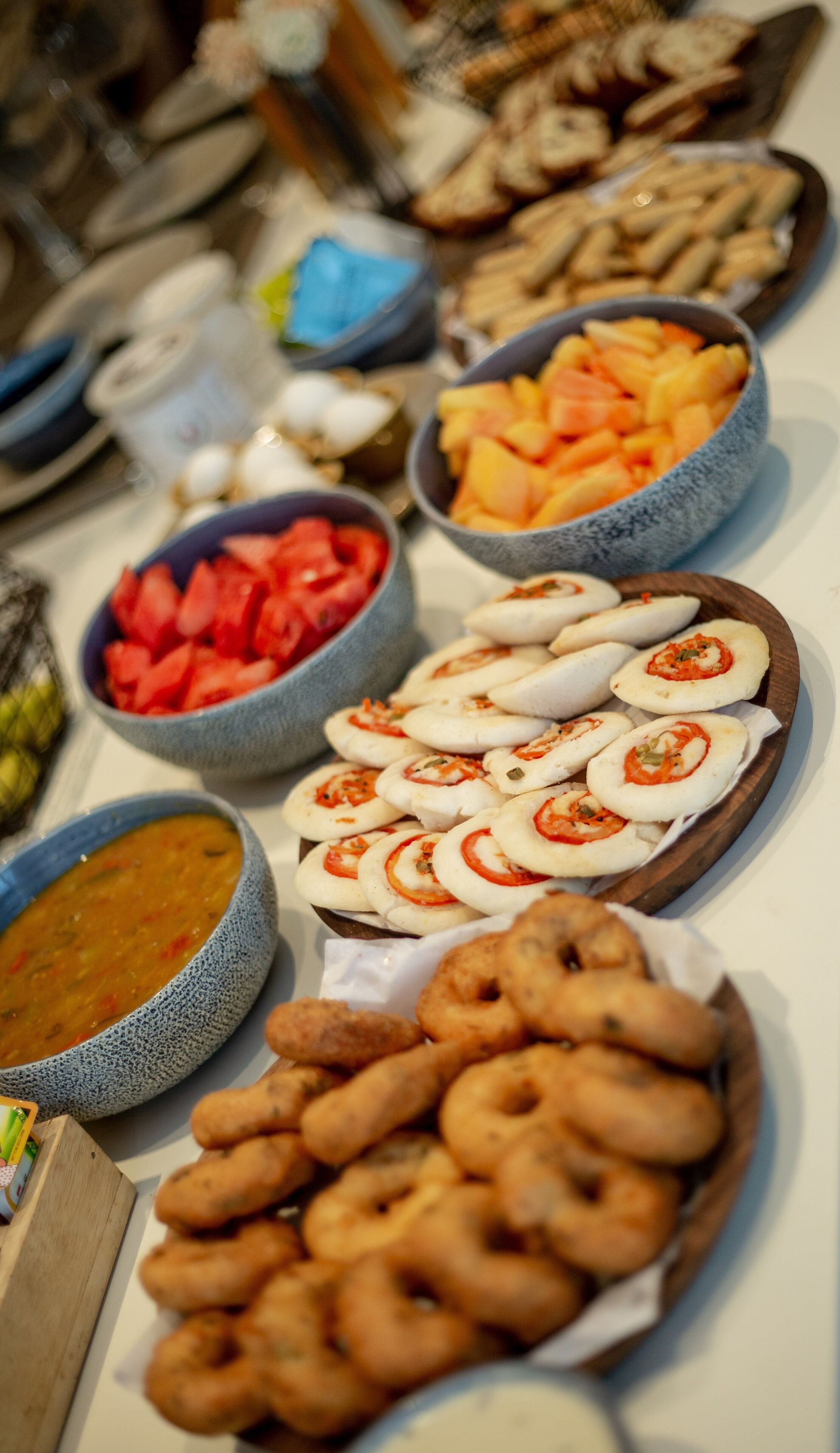 Un buffet proposant une variété de plats, notamment des fruits et des légumes coupés en tranches, ainsi que différents types de pain.
