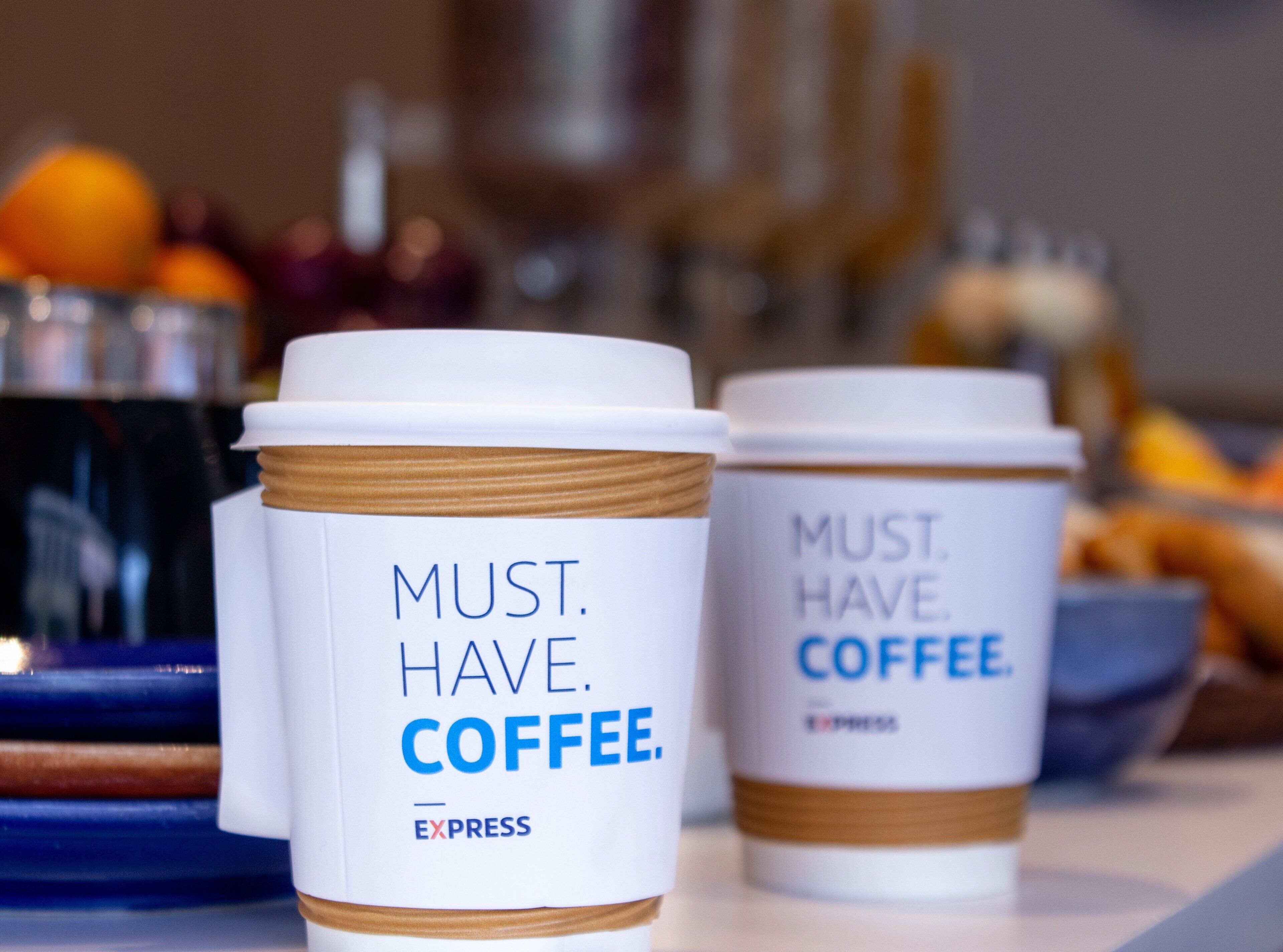 Two coffee cups with the text 'MUST HAVE COFFEE' and 'EXPRESS' on them.