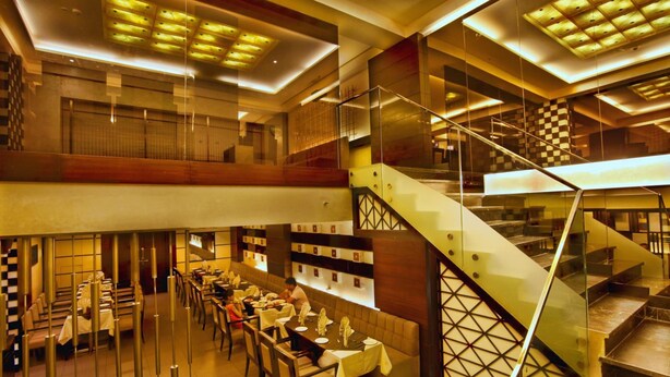 A spacious hotel lobby with a modern staircase, multiple dining areas, and a well-lit ceiling. - Hotel Caspia Pro Greater Noida (Greater Noida)