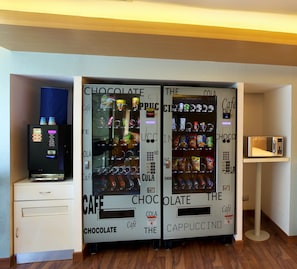 Een kamer met twee automaten, genaamd 'Chocolate' en 'The Cappuccino', met diverse snacks en drankjes.