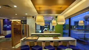A modern indoor space with a long table, multiple chairs, and pendant lighting. - Hotel Caspia Pro Greater Noida (Greater Noida)