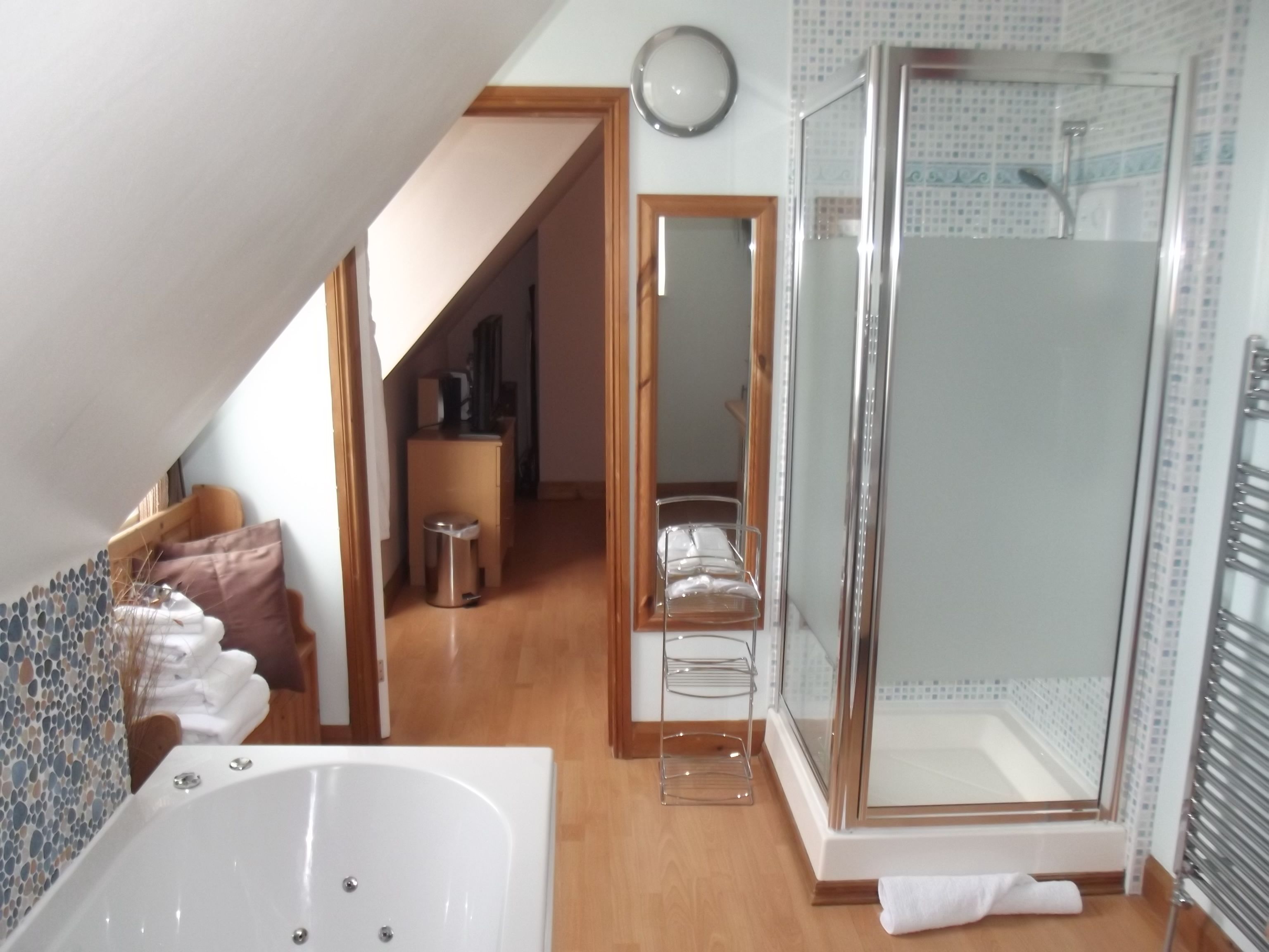 A modern bathroom with a bathtub, shower, and a mirror.