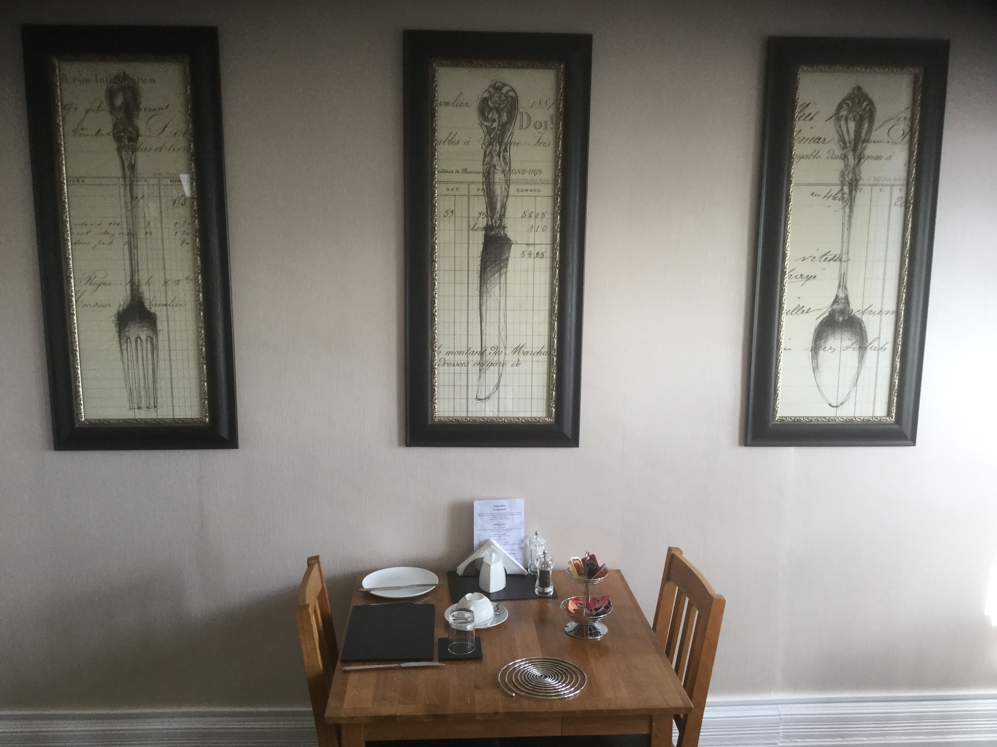A dining table with a menu, a glass, a salt shaker, and a napkin holder.