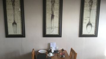 A dining table with a menu, a glass, a salt shaker, and a napkin holder.