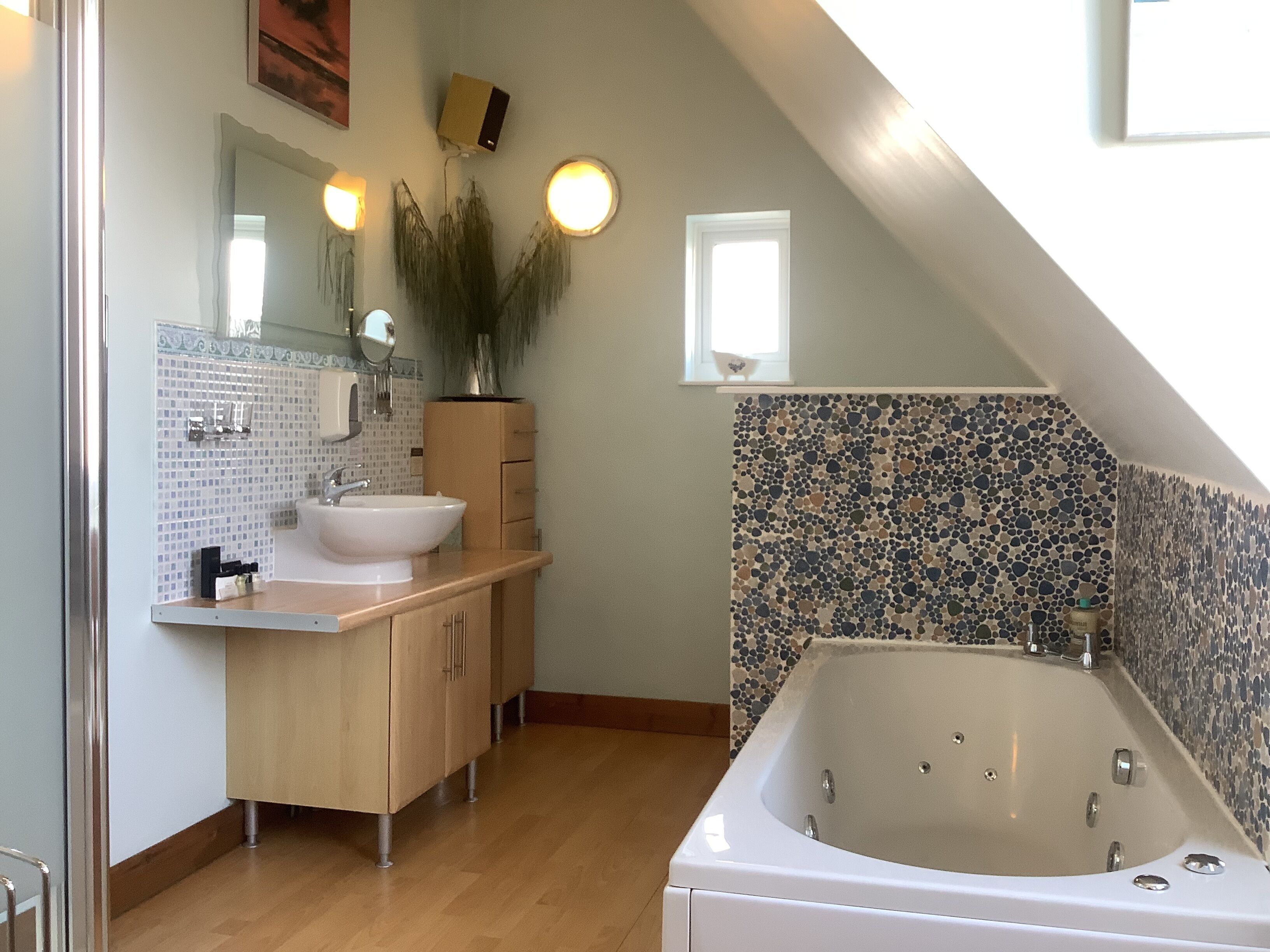 Un bagno moderno con una vasca da bagno indipendente, un mobile vanitario con lavandino e uno specchio.