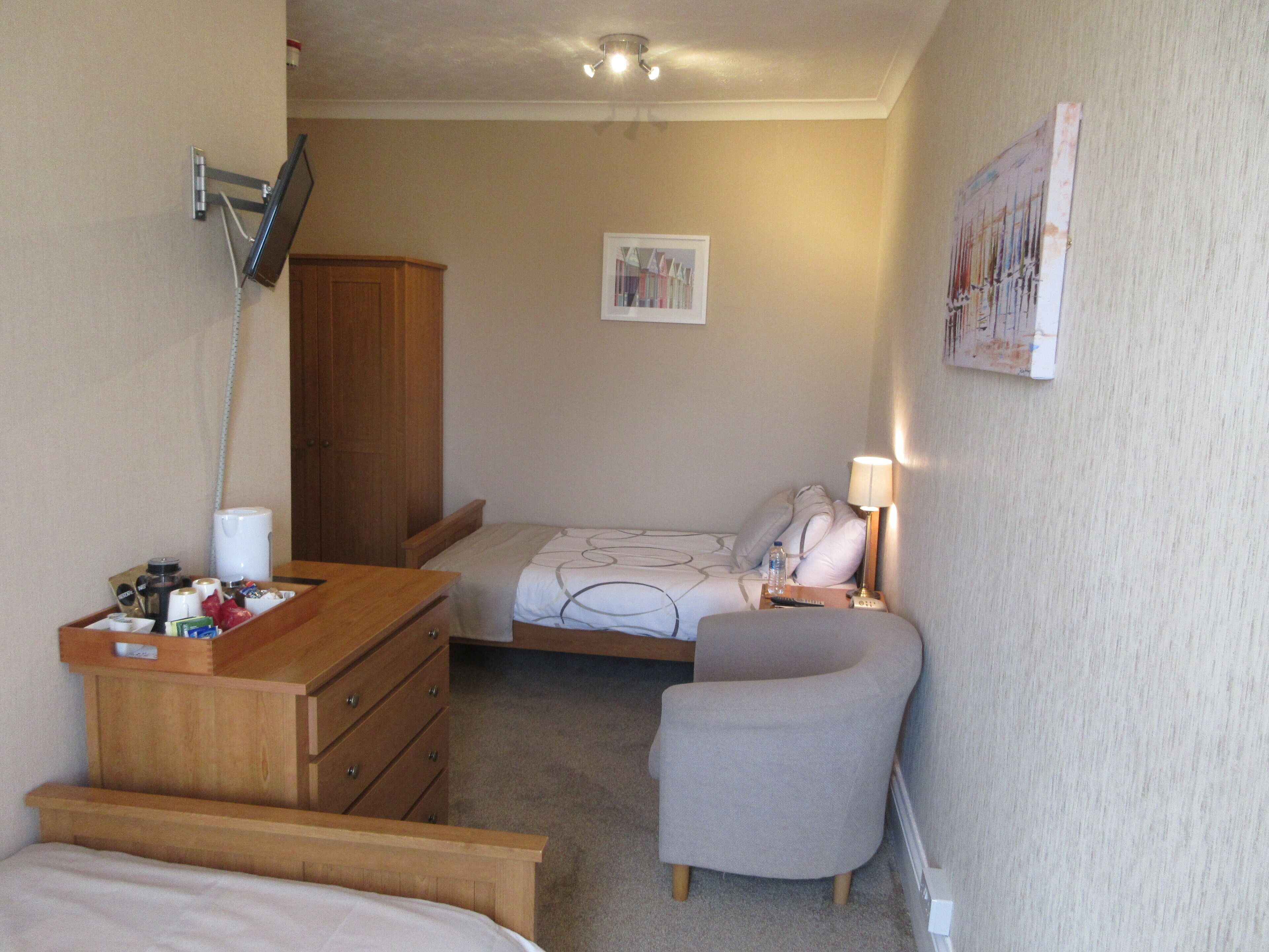 Une petite chambre à coucher, bien rangée, avec un lit, une chaise, un bureau et une armoire.