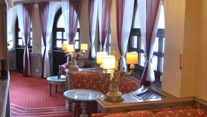 A hotel room with a red carpet, a sofa, a dining table with lamps, and curtains. - Hotel & Residence Catturani (Pinzolo)