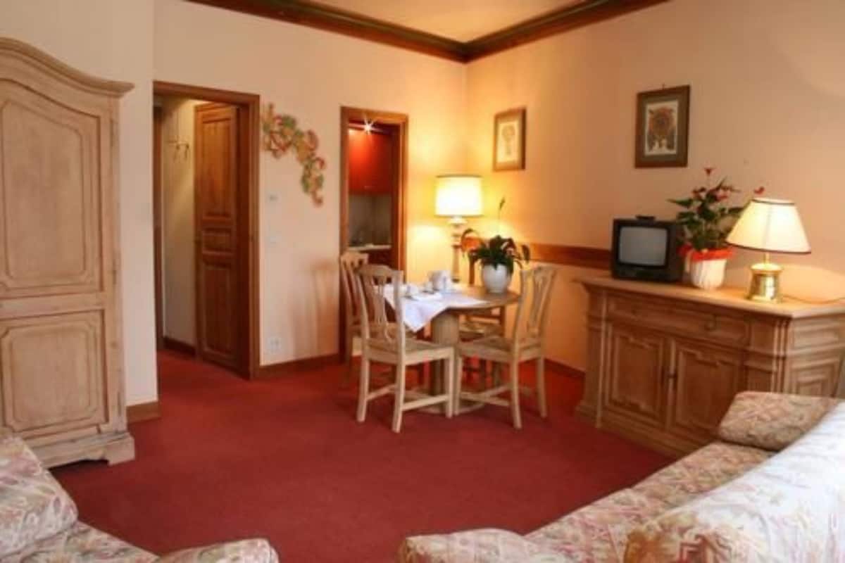A hotel room with a dining table, chairs, a television, and a cabinet.