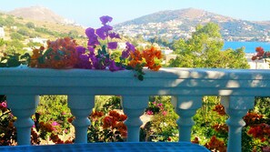 A balcony with a view of a hillside town and a body of water. - Angelika (Leros)