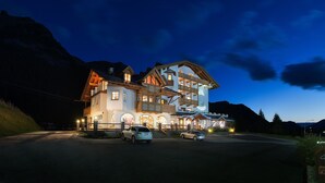 A large, multi-story hotel with a traditional Alpine architectural style, featuring balconies and a well-lit facade. - Hotel Cristallo (Moena)
