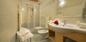 Un baño con ducha, inodoro, bidé y lavamanos.