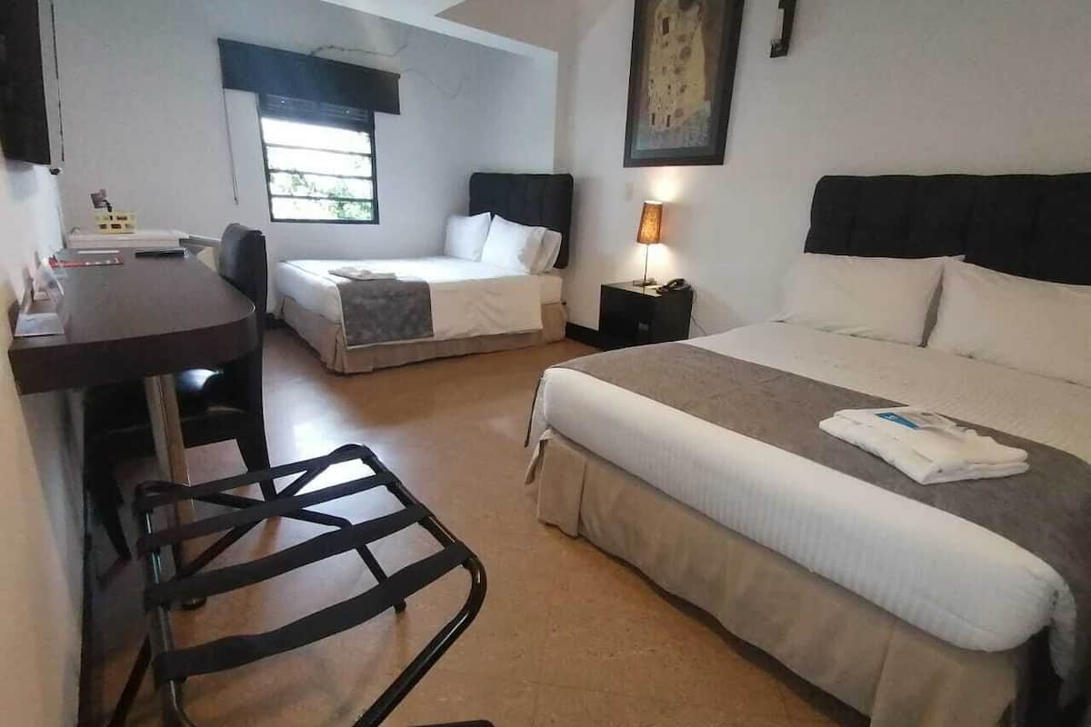 A hotel room with a bed, a desk, and a chair.