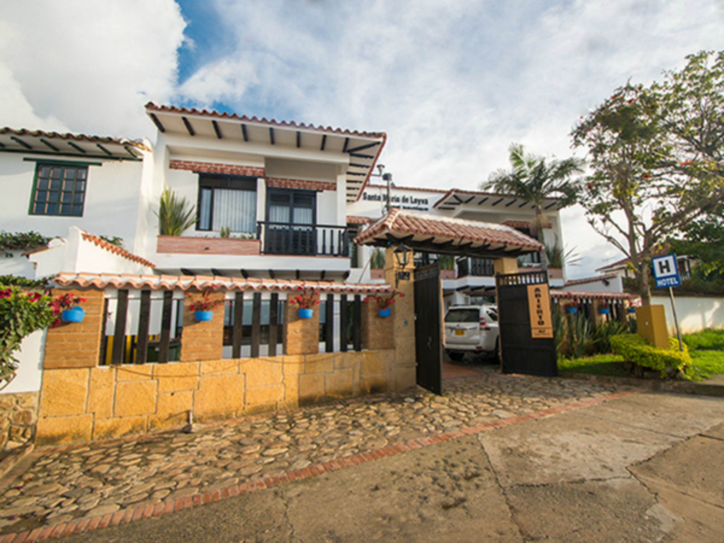Una casa de dos pisos con techo de tejas, entrada con reja y un letrero que indica un hotel.