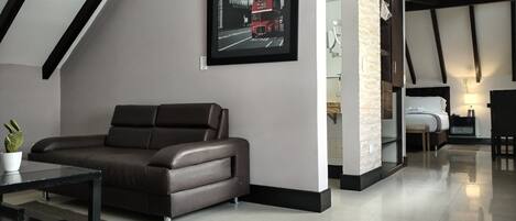 A modern living room with a brown leather sofa, a glass coffee table, and a framed picture of a red double-decker bus.