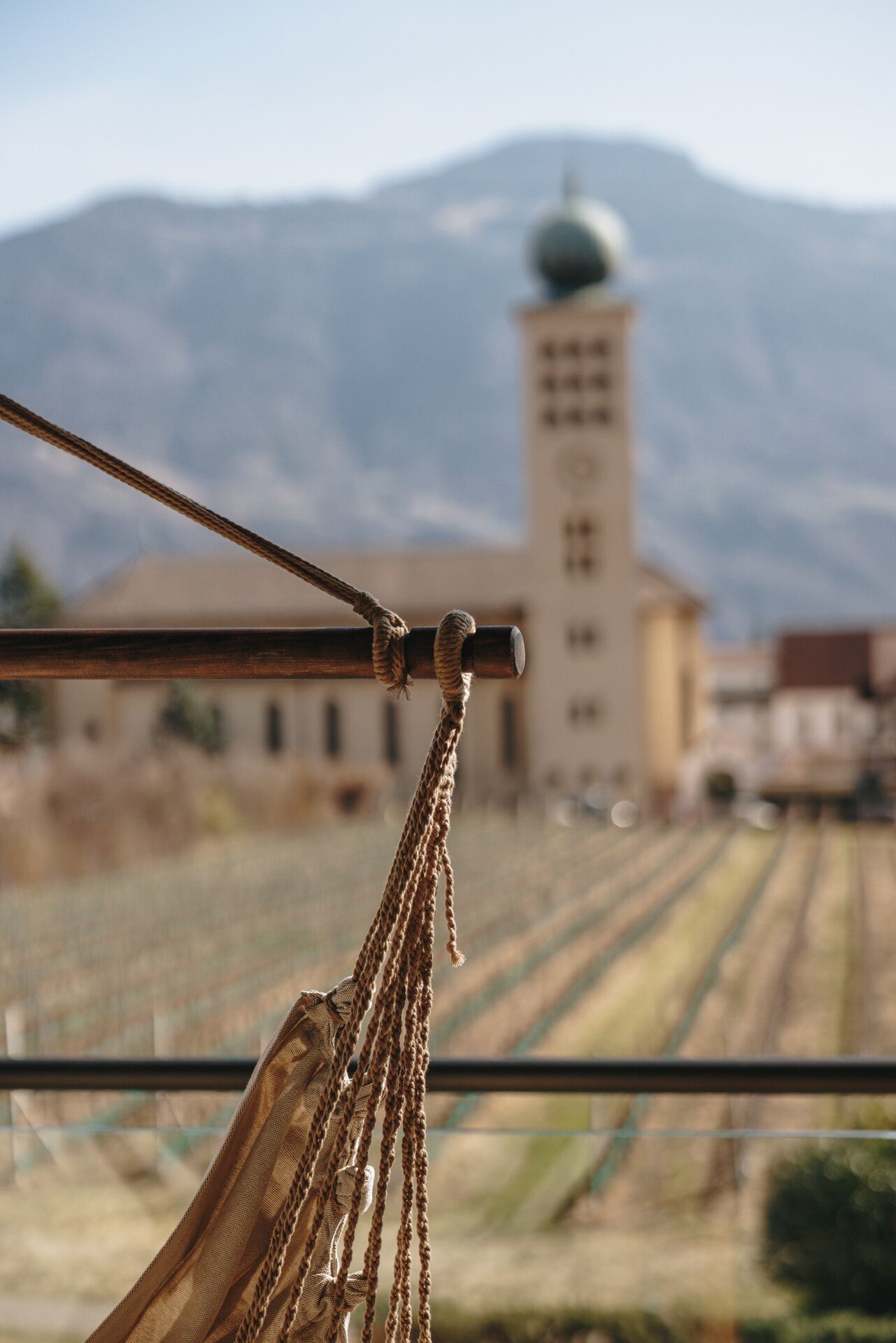 A rope tied to a metal pole with a view of a building and mountains in the background.