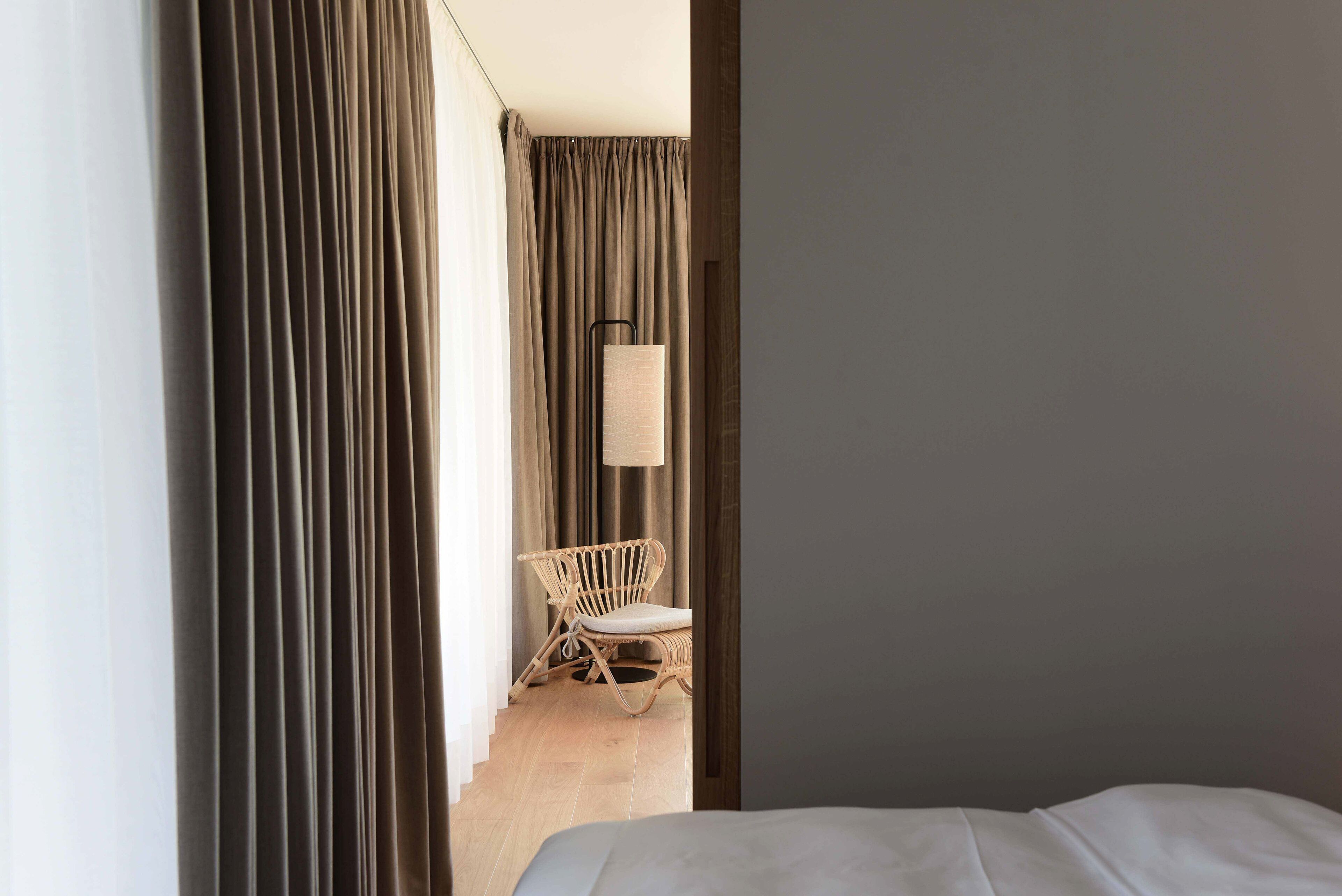 Una camera d'albergo con un letto, una sedia e tende.
