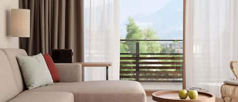 Una sala de estar moderna con un sofá, una mesita con manzanas, una lámpara y vistas a las montañas a través de amplios ventanales.