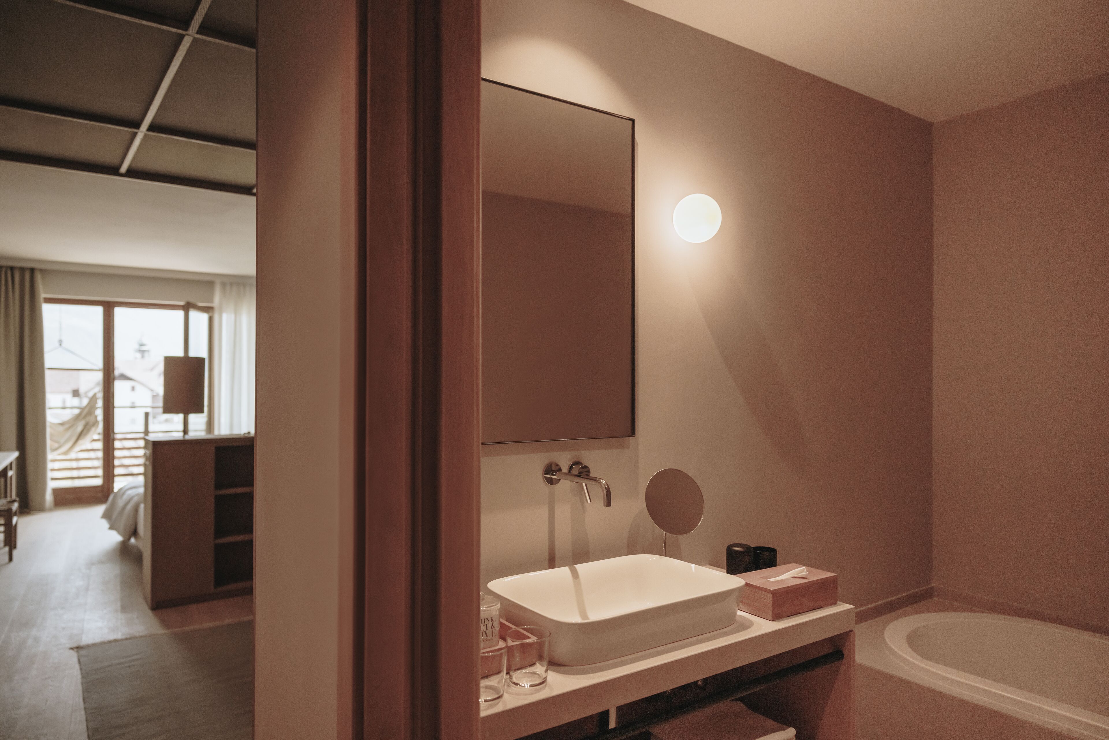 A modern bathroom with a large mirror, a sink, and a bathtub.