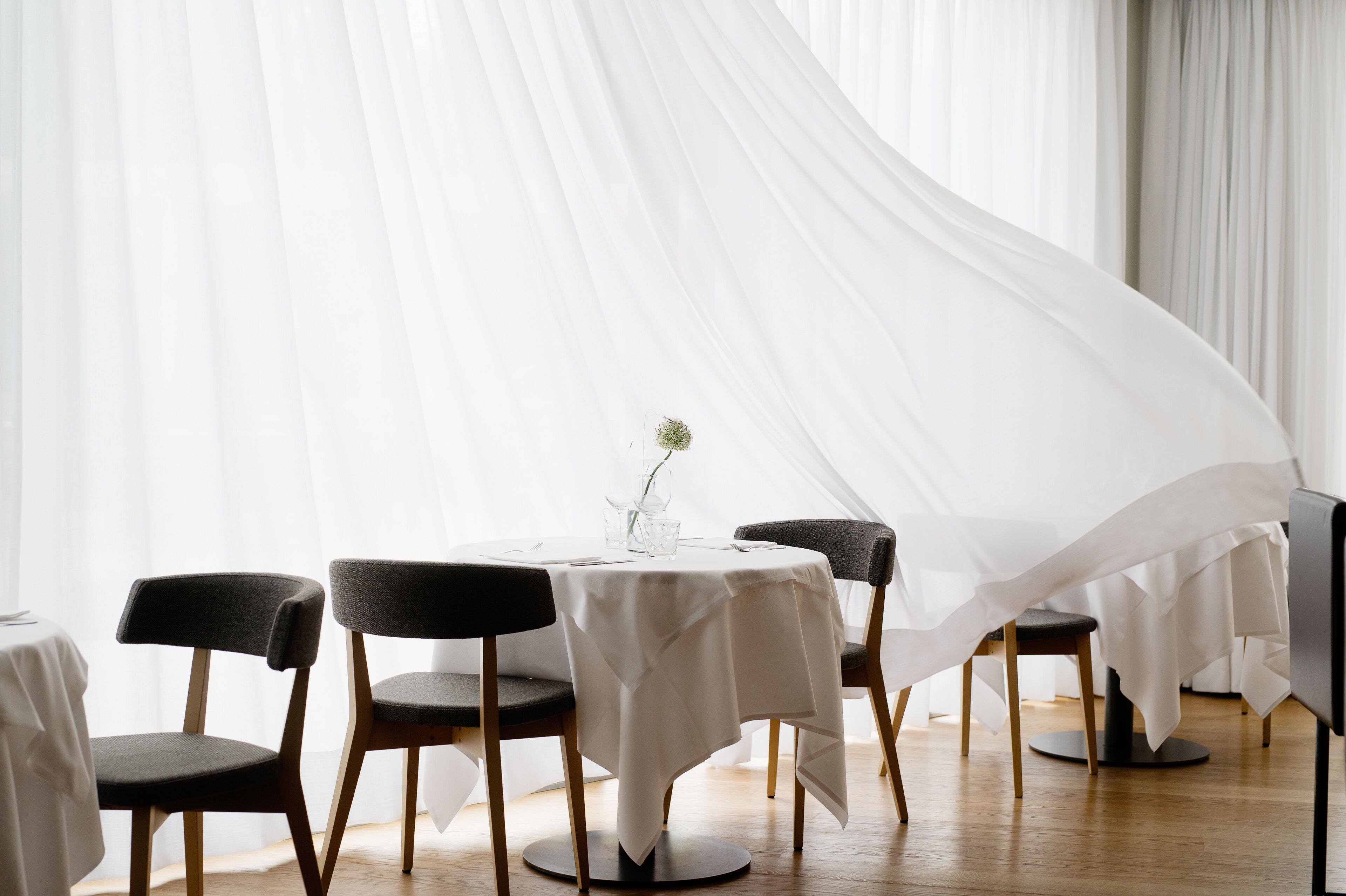 A dining area with a round table, four chairs, and a white tablecloth.