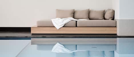 Ein modernes Wohnzimmer mit einem beige farbenen Sofa, einer weißen Decke und einem spiegelnden Boden.