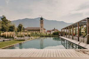 Una piscina techada, una piscina al aire libre, sombrillas