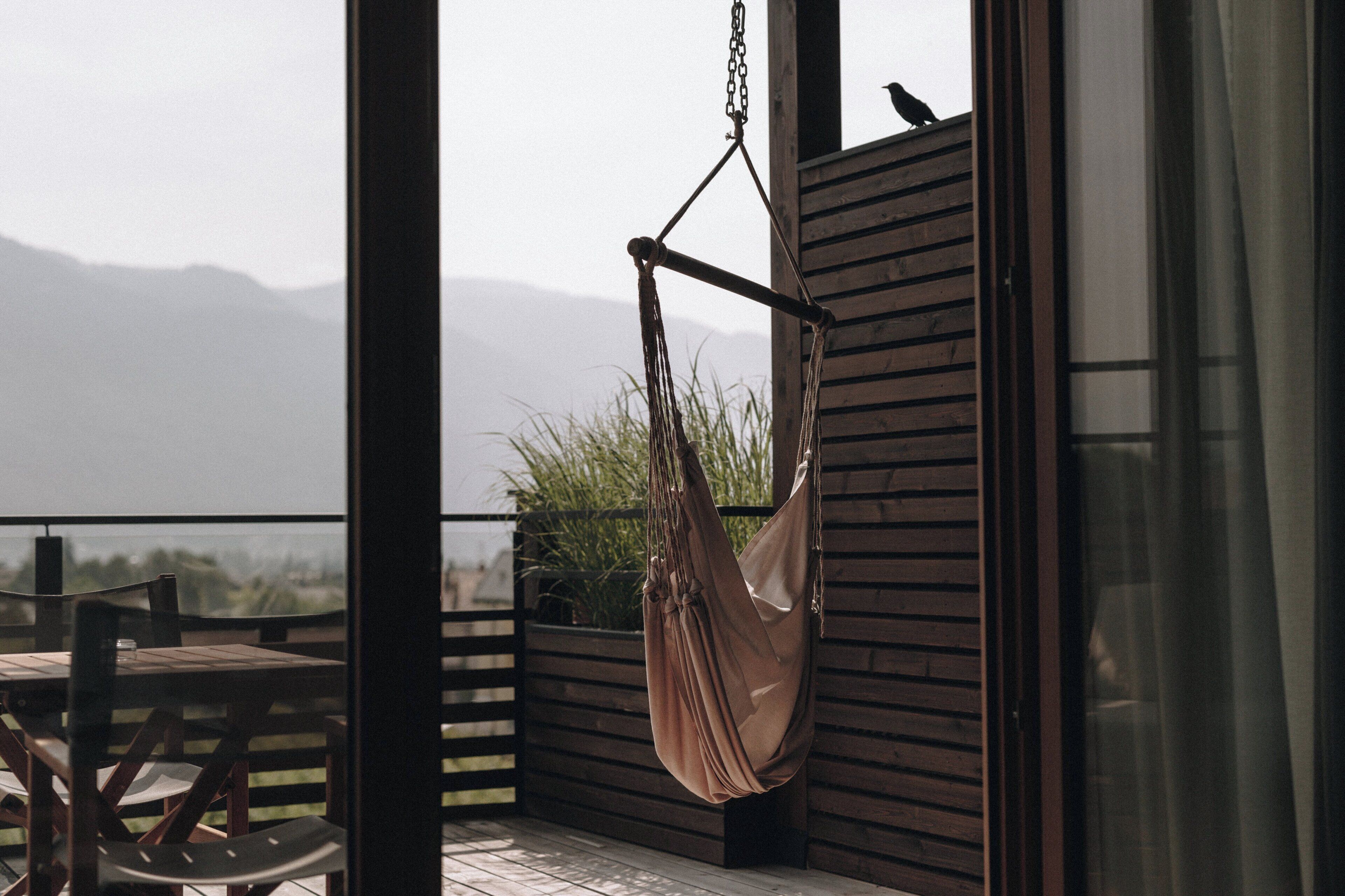 A hammock hanging on a balcony with a view of mountains.