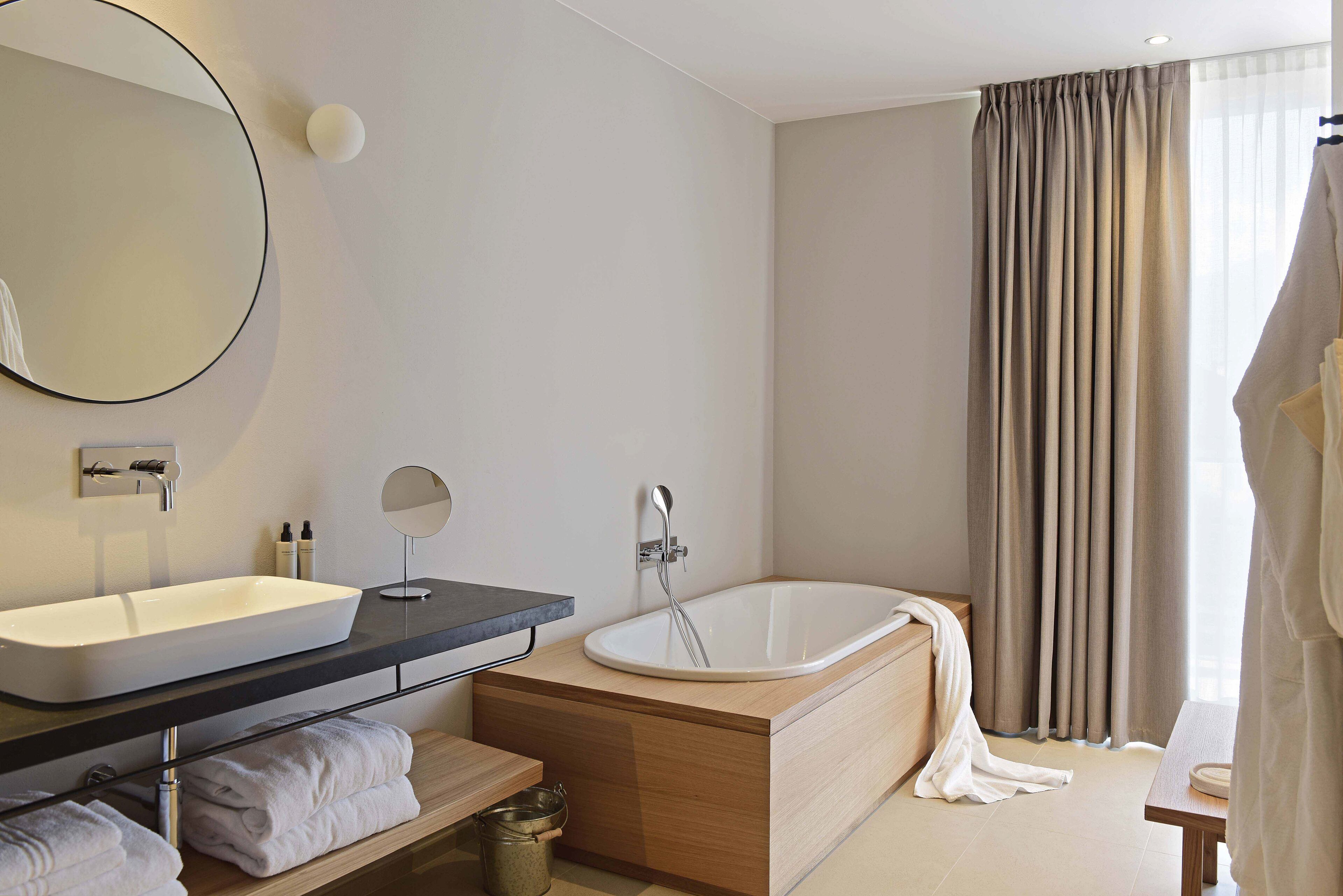 A modern bathroom with a large sink, a bathtub, and a mirror.