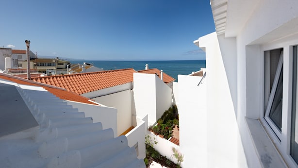 Un bâtiment blanc avec un toit recouvert de tuiles rouges, un escalier et une vue sur la mer.