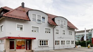 Un bâtiment doté d’une entrée centrale, de nombreuses fenêtres et d’une enseigne indiquant qu’il abrite un restaurant, un café, un bar et un hôtel.