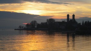 Un coucher de soleil sur une étendue d’eau, avec la silhouette d’une ville et une tour imposante.