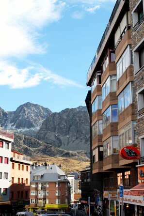Une ville de montagne où se côtoient des bâtiments modernes et traditionnels, avec un ciel dégagé et une chaîne de montagnes en toile de fond.