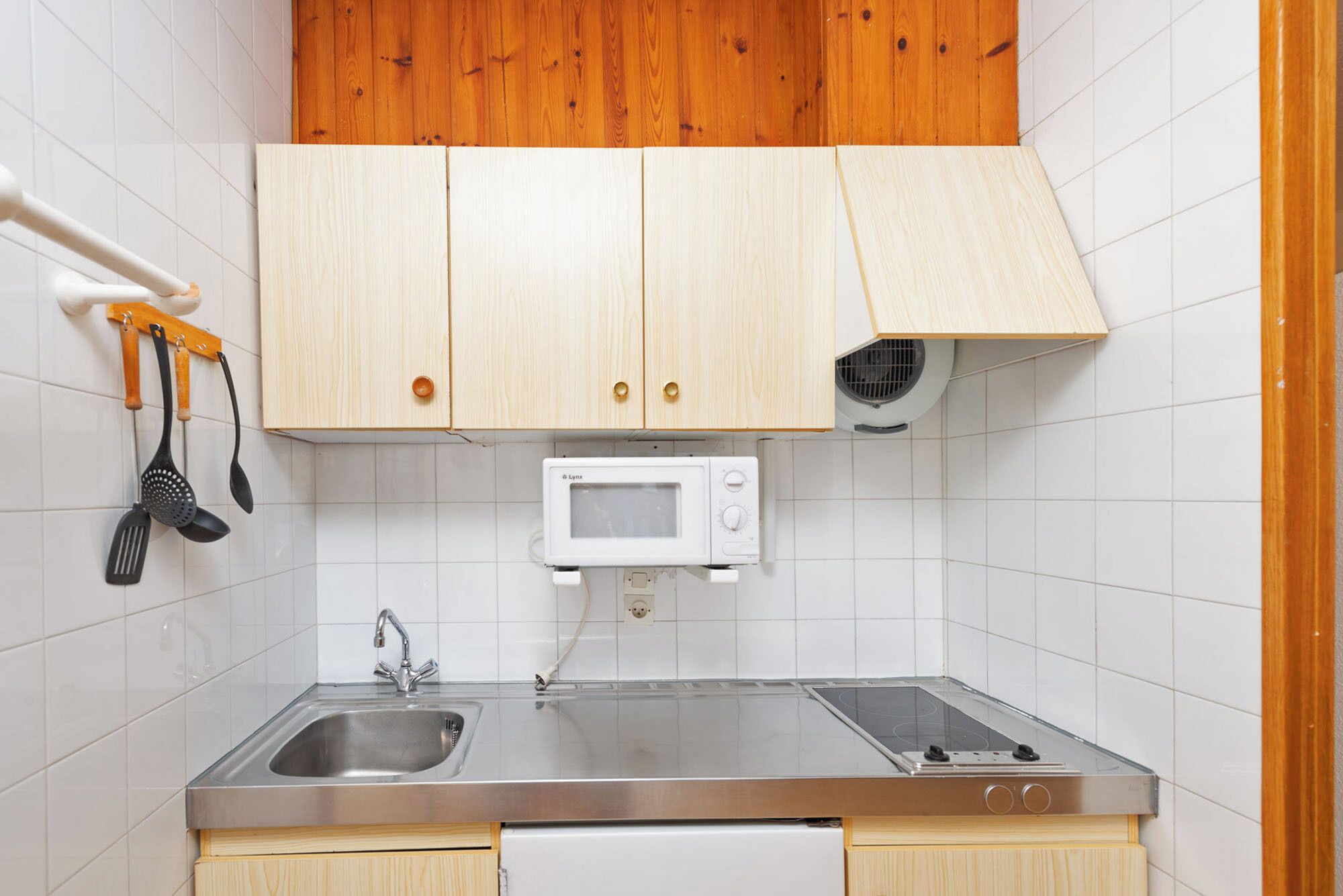 Eine Küche mit Holzausstattung, einer Edelstahlspüle, einer Mikrowelle und einem Herd.