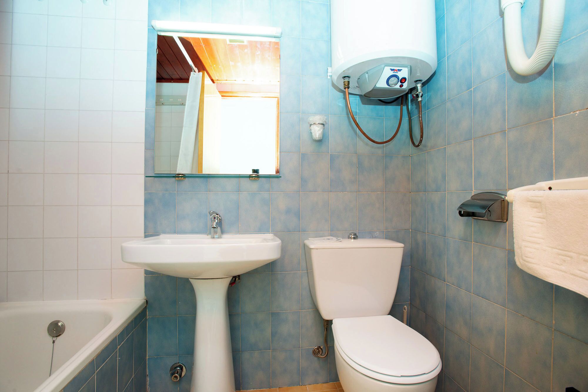 Et badeværelse med et håndvaskestel, toilet og badekar.