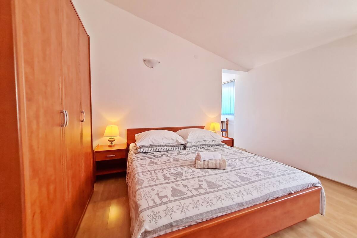 A bedroom with a wooden bed, a nightstand with a lamp, and a wardrobe.