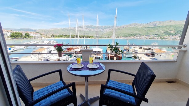 A balcony with two chairs and a table, overlooking a marina with boats and a hilly landscape. - Apartments Rooms PORAT (Split)