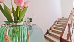 A staircase with a wooden handrail and a green vase with pink flowers on a table. - Apartments Rooms PORAT (Split)