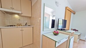 A modern kitchen with beige cabinetry, a built-in stove, and a large mirror above the countertop. - Apartments Rooms PORAT (Split)