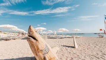 Praia particular, espreguiçadeiras, guarda-sóis, prática de windsurfe